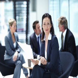 Portrait of business woman smiling with executives discussing in background